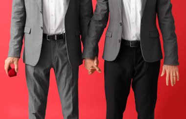 Kırmızı arka planda mutlu nişanlı eşcinsel çift