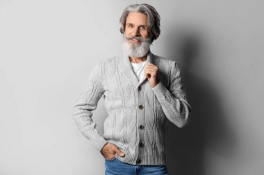 Gri arka planda örgü süveter giyen yakışıklı bir ihtiyar.