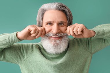 Yeşil arka planda örgü süveter giyen mutlu kıdemli adam.