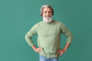 Yeşil arka planda örgü süveter giyen yakışıklı bir adam.