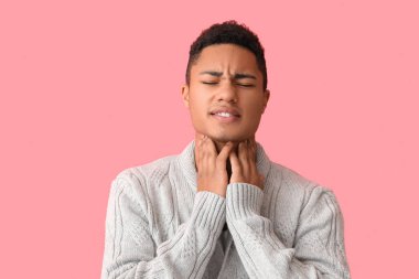 Arka planda boğazı ağrıyan Afro-Amerikalı bir adam.
