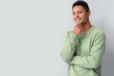 Hafif arka planda örgü süveter giyen yakışıklı Afro-Amerikalı adam.