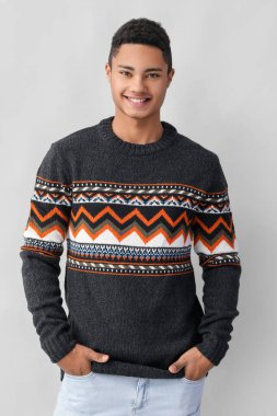 Hafif arka planda örgü süveter giyen yakışıklı Afro-Amerikalı adam.