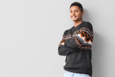 Hafif arka planda örgü süveter giyen yakışıklı Afro-Amerikalı adam.