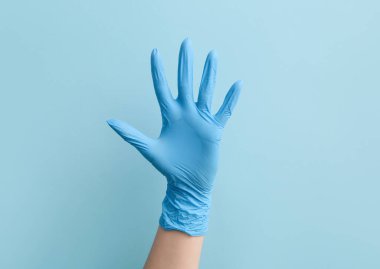 Mavi arka planda tıp eldivenli kadın doktor.