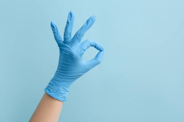 Tıbbi eldivenli kadın mavi arka planda iyi görünüyor.