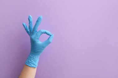 Tıbbi eldivenli kadın menekşe arka planda iyi görünüyor.