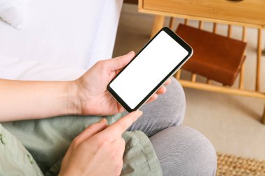 Cep telefonu kullanan bir kadın evde boş ekranlı, yakın plan.