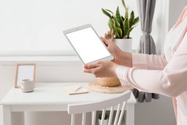 Tablet bilgisayarı olan kadın evdeki masanın yanında, yakın plan.