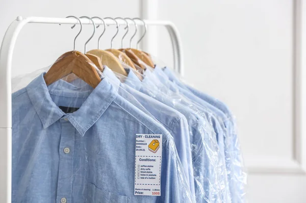 Rack Com Camisas Limpas Sacos Plástico Perto Parede Leve — Fotografia de Stock