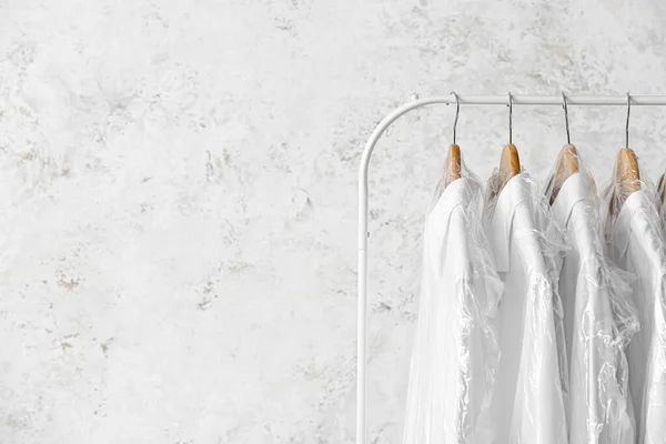 Стойка Чистыми Белыми Рубашками Пластиковых Пакетах Фоне Гранжа — стоковое фото