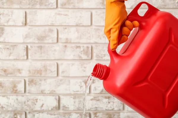 Mann Schüttet Flüssigkeit Aus Plastikkanister Nahe Ziegelmauer Aus — Stockfoto