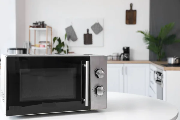 Microwave oven on white table in light kitchen