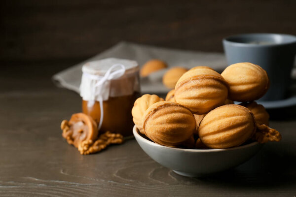 Bowl of tasty walnut shaped cookies with boiled condensed milk on dark wooden table