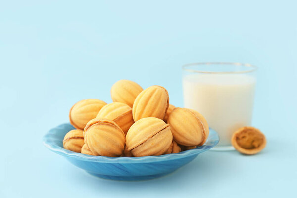 Plate of tasty walnut shaped cookies with boiled condensed milk on blue background