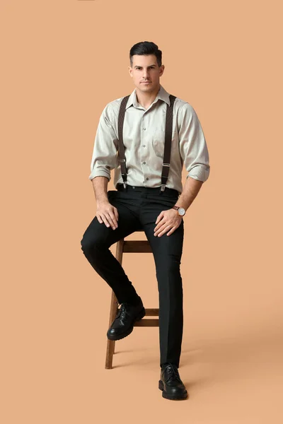 色の背景を背景に椅子に座っているファッショナブルな紳士 — ストック写真