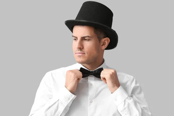 Caballero Moda Sombrero Cilindro Ajustando Corbata Lazo Sobre Fondo Gris — Foto de Stock