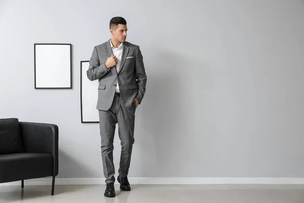 ハンサムな男でエレガントなスーツ近くの灰色の壁に部屋で — ストック写真