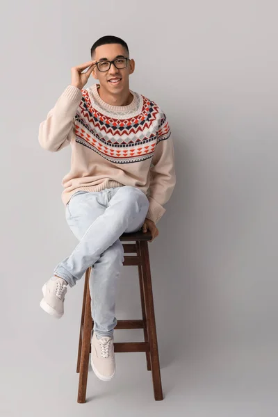 Gri Arka Planda Sandalyede Oturan Örgü Örülü Genç Asyalı Yakışıklı — Stok fotoğraf