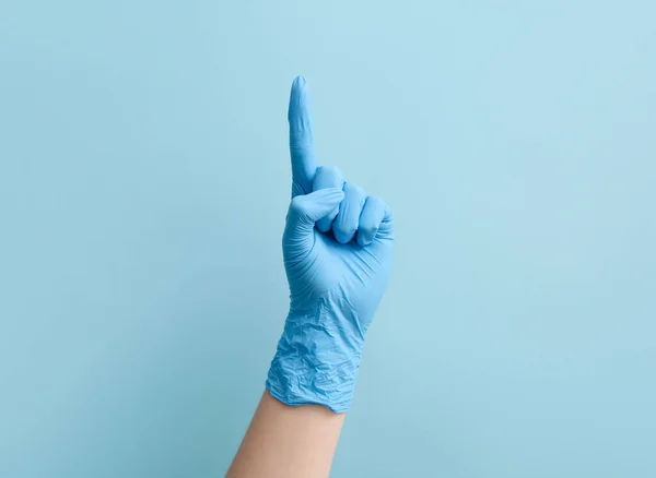 女性医師で医療手袋で何かを指す上で青の背景 — ストック写真