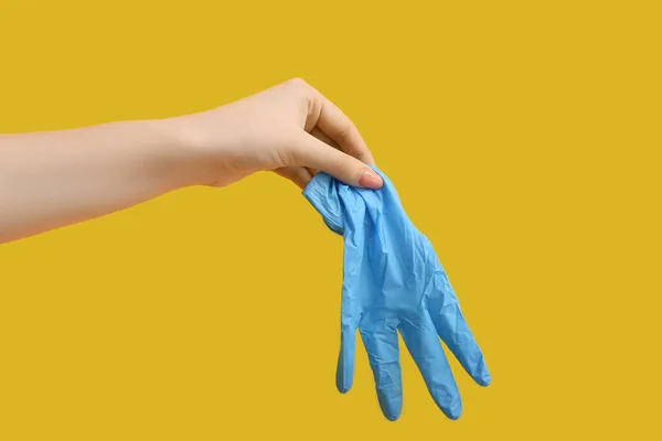 黄色の背景に青い医療用手袋を持つ女性 — ストック写真