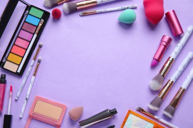 Mor arkaplanda farklı makyaj ürünlerinden yapılmış çerçeve