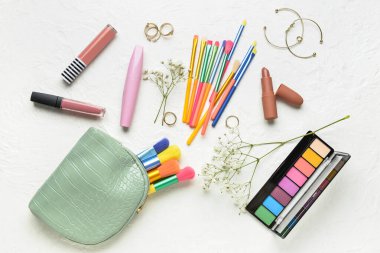 Hafif arkaplanda makyaj fırçaları ve kozmetik ürünleri olan çanta