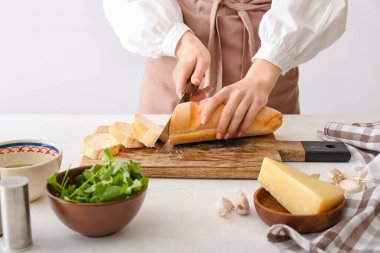 Mutfak masasında ekmek hazırlamak için ekmek kesen kadın, yakın plan.