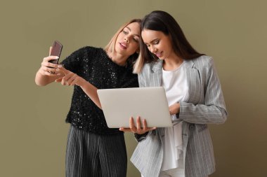 Dizüstü bilgisayarı ve renkli cep telefonu olan genç kadınlar