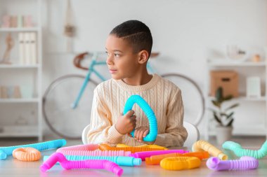 Küçük Afro-Amerikalı çocuk evde Pop Tube ile oynuyor.