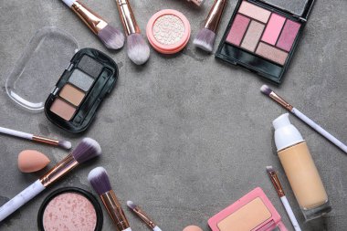 Koyu arkaplanda makyaj fırçaları ve dekoratif kozmetiklerden yapılmış çerçeve