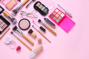 Ahşap makyaj fırçaları ve pembe arka planda dekoratif kozmetik ürünler.