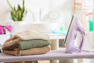 Çamaşır odasında elektrikli ütü ve kazak yığını var.