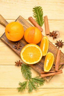 Tahtada taze portakallar ve tahta arka planda köknar dalları var.