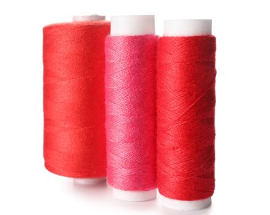 Beyaz arkaplanda pembe ve kırmızı dikiş ipliği makaraları