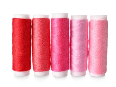Beyaz arkaplanda pembe ve kırmızı dikiş ipliği makaraları