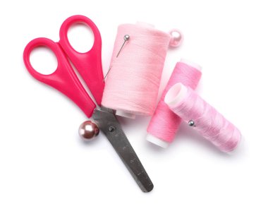 Beyaz arkaplanda iğne ve makas bulunan pembe dikiş ipliği makaraları