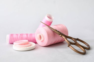 İplik makaraları, makas ve ışık arkaplanındaki düğmeler dikiliyor