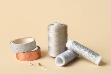 Işık arkaplanındaki iplik makaraları, iğneler ve bantlar dikiliyor