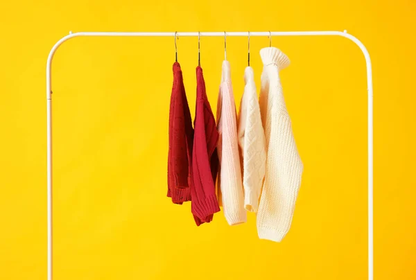 Kleiderständer Mit Strickpullovern Auf Farbigem Hintergrund — Stockfoto