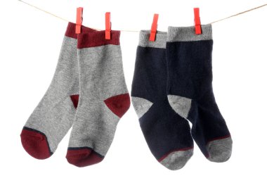 Beyaz arka planda ipte asılı farklı pamuk çoraplar, yakın plan