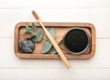 Aktif kömür diş tozu, taş ve beyaz ahşap arka planda fırça ile kase