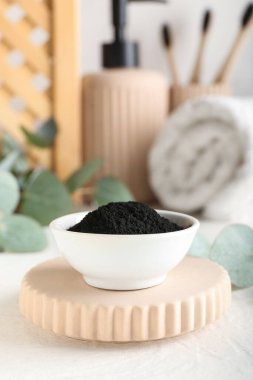 Masanın üzerinde aktif kömür dişi tozu olan bir kase.