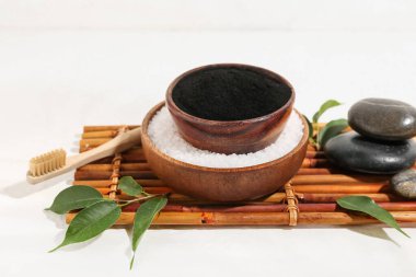 Aktif kömür diş tozu ve beyaz arka planda deniz tuzu olan kaseler.