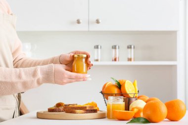 Mutfakta lezzetli portakal reçeli kavanozu olan bir kadın.