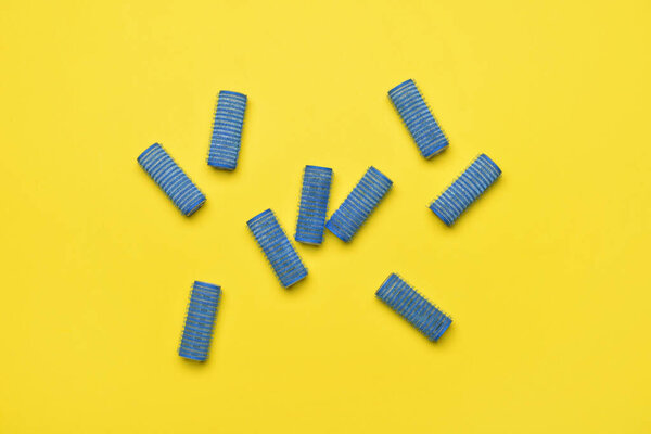 Blue hair curlers on yellow background