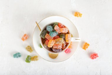 Arka planda farklı jöle ayıcıkları olan fincan.