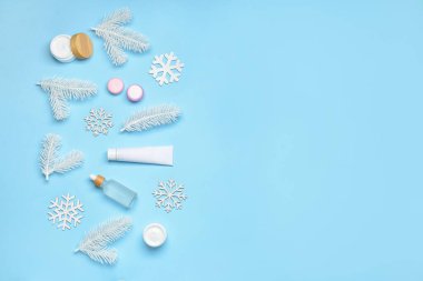 Renk arkaplanında kış dekoru ve farklı kozmetik ürünleri içeren kompozisyon