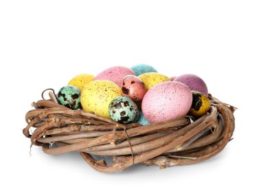 Beyaz arka planda renkli Paskalya yumurtaları olan bir yuva.