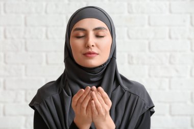 Müslüman kadın tuğla arka planda dua ediyor